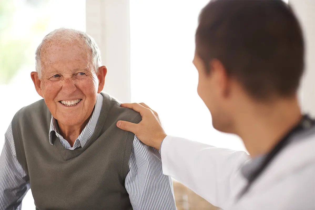 Senior man smiling at a doctor with his hand on his shoulder