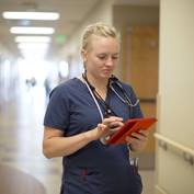 A nurse takes notes on a tablet device.