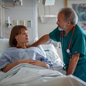 A doctor speaks with his patient at her bedside.
