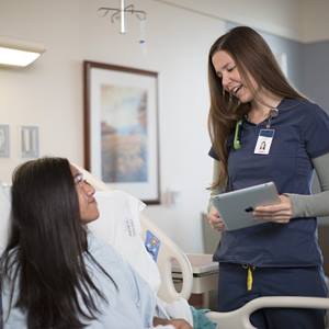 A nurse holds a bedside discussion with a patient.