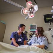 A nurse holds a bedside conversation with a patient.