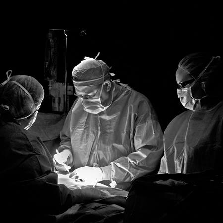 A surgeon performs a procedure on the operating table.