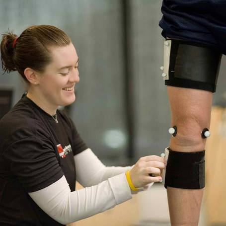 A female physical therapist adjusts the straps on a patient's leg