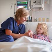 senior-female-nurse-checks-girls-pulse-in-hospital-bed