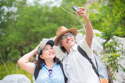 happy younger Asian couple hiking in warm weather taking a selfie