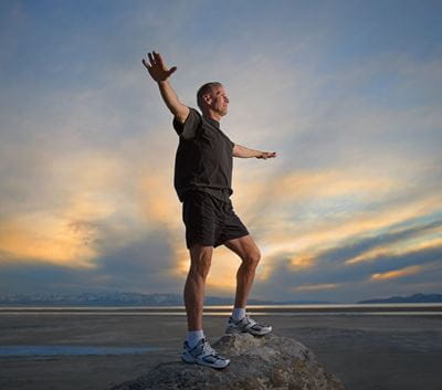 Man Balancing on Rock at Sunset