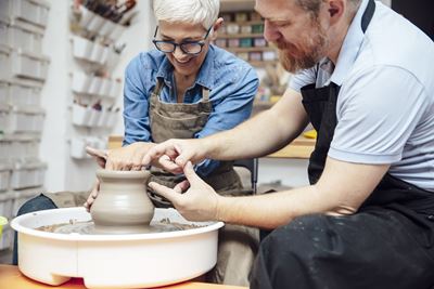 older woman learning how to make pottery at a pottery wheel 