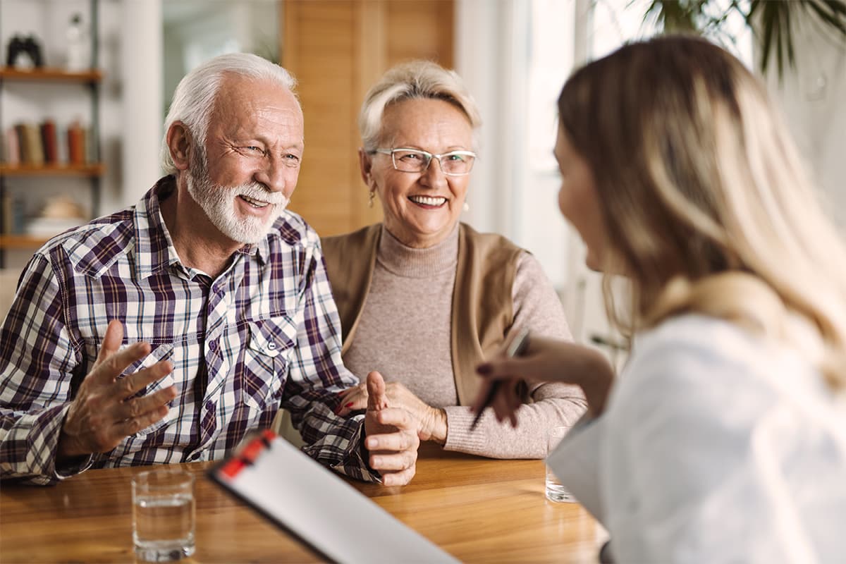 Senior man and woman sitting at a table talking to a doctor