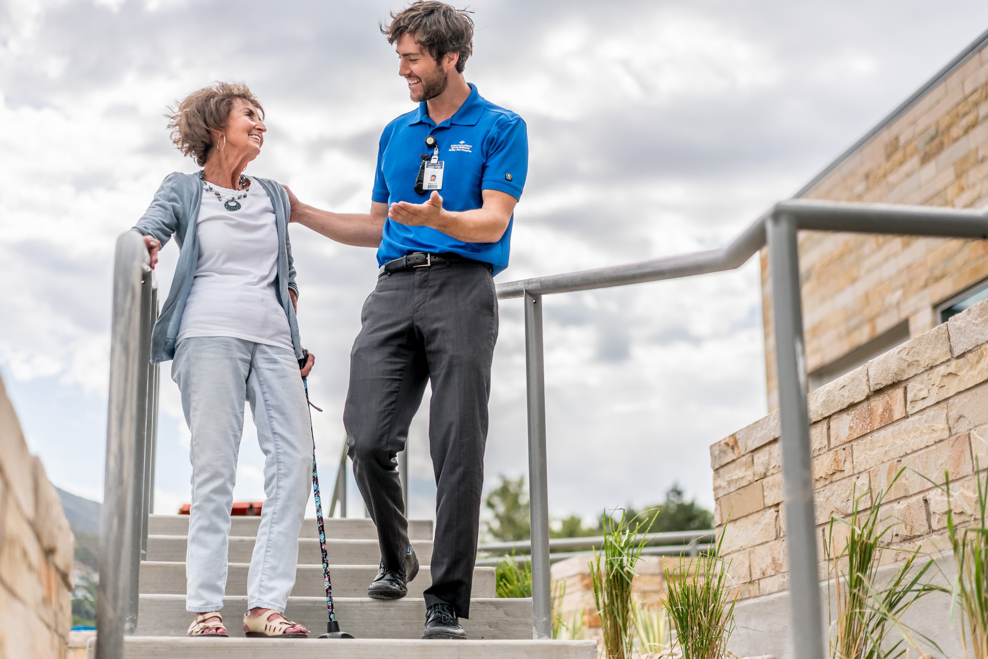 A caregiver helping a patient walk down a flight of stairs