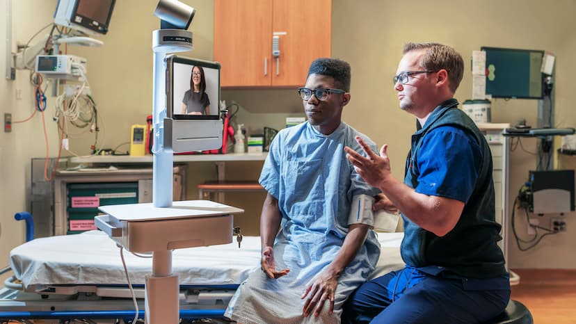 patient and provider in hospital room talking to a telehealth provider on screen