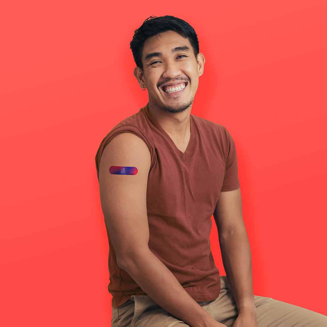 Young Asian man smiling with a band aid on his arm after receiving flu shot