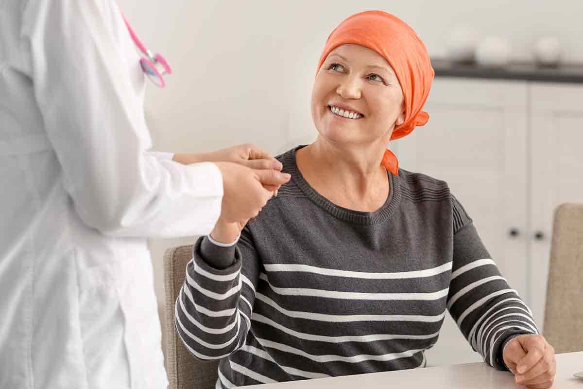 Cancer patient in and orange head scarf with physician