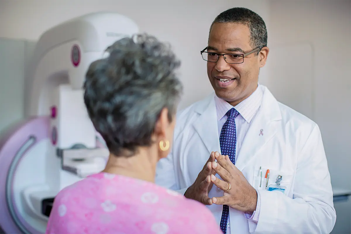 Senior woman talking to a doctor with an MRI machine in the background